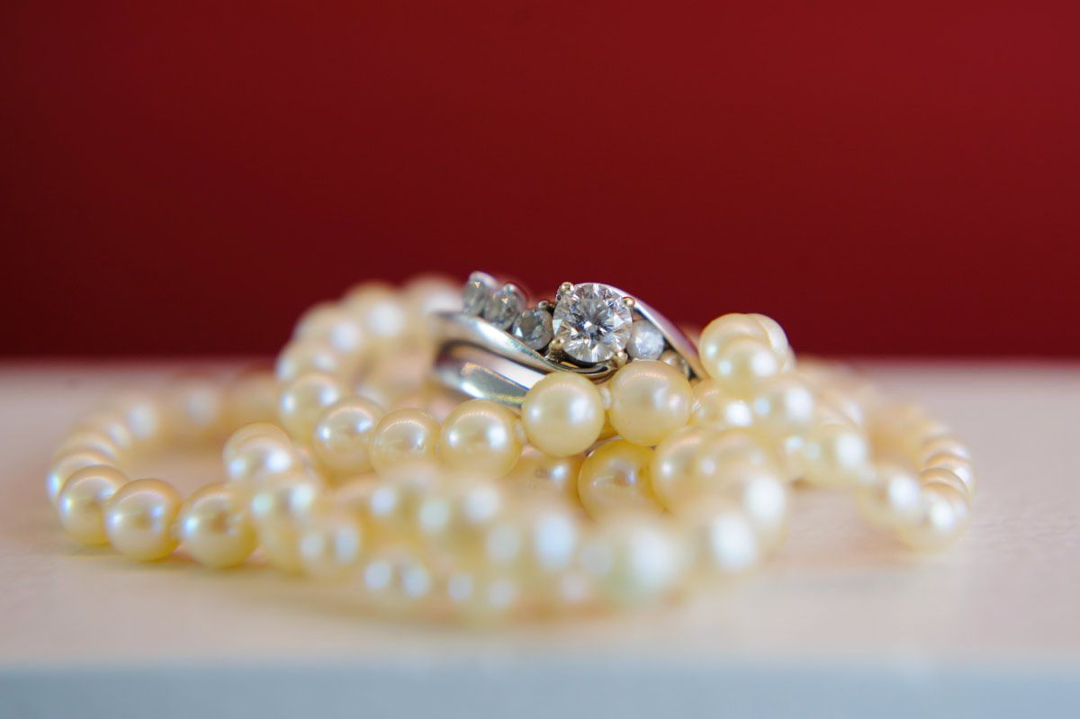 Closeup of a wedding ring set on top of a white pearl necklace